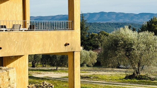 Een geel gebouw met balkon en uitzicht op een bergachtig landschap.