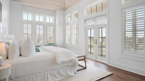 A bedroom with a large bed, multiple windows, and a view of the outdoors.