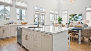 Una cocina amplia con una isla grande, armarios blancos y vistas al vecindario.