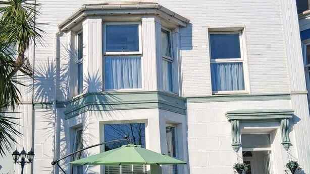 A two-story building with a bay window, a green awning, and a front door. - The Barbican Hotel (Paignton)