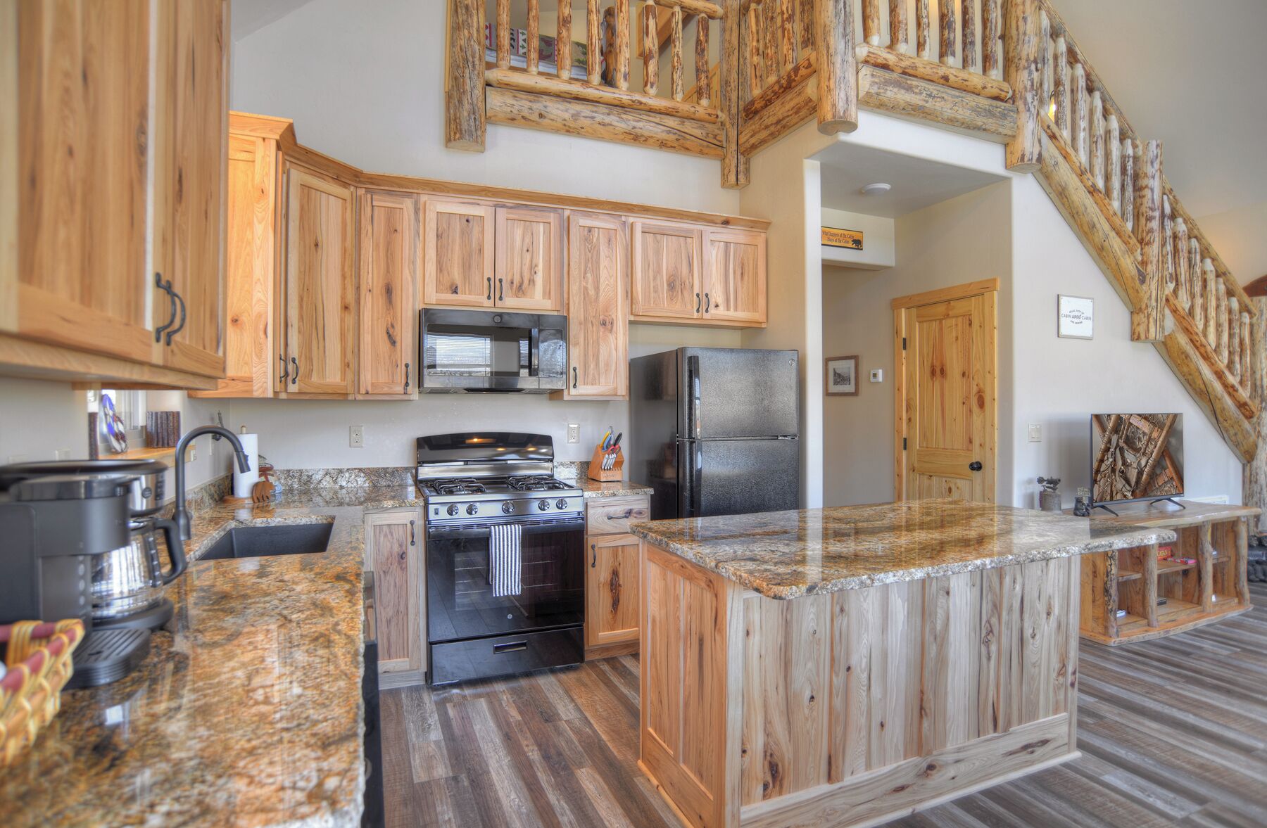 A kitchen with wooden cabinets, a stove, a refrigerator, and a granite countertop.