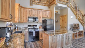 Una cocina con armarios de madera, estufa, refrigerador y encimera de granito.
