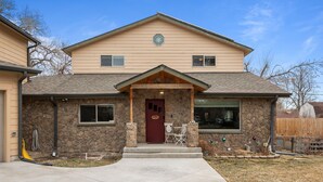 A two-story house with a stone facade, a red front door, and a small porch with outdoor seating. - Hot Tub & Gym | Minutes to Red Rocks Ampitheater | Sauna (Lakewood)