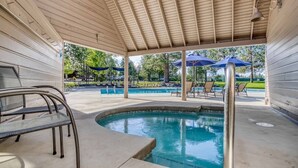 A covered pool area with a wooden ceiling, lounge chairs, and umbrellas. - Mt. Bachelor Village Escape: Hot Tub, Pool, Fireplace & Central Bend Location (Bend)