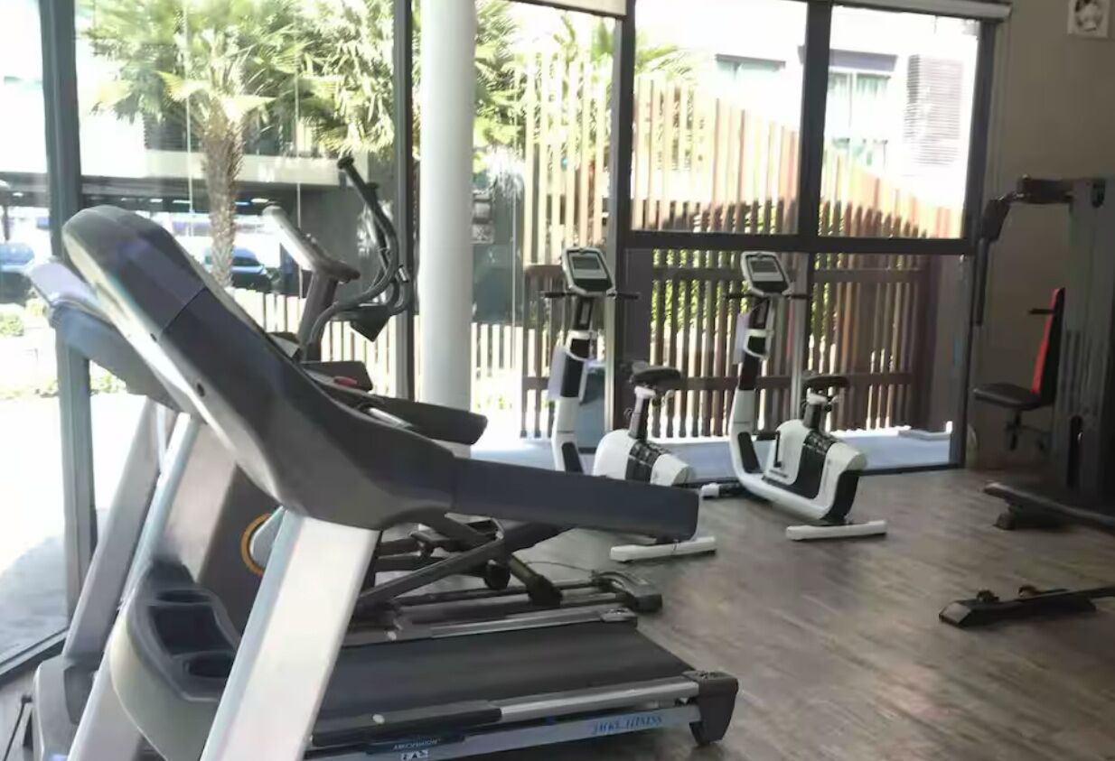 Et fitnessrum med løbebånd, crosstrainere og en romaskine.