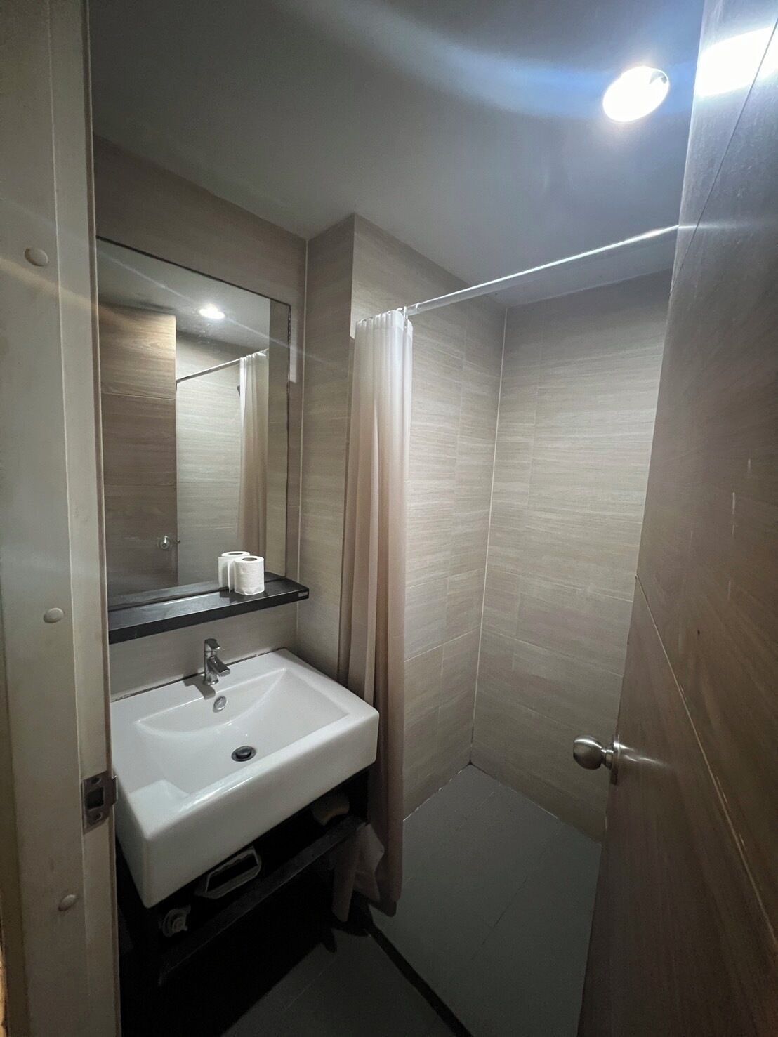 Une salle de bain avec un lavabo blanc, un miroir et un rideau de douche.