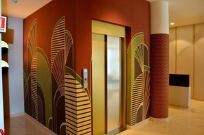 Elevator area with abstract leaf patterned wall and control panel.