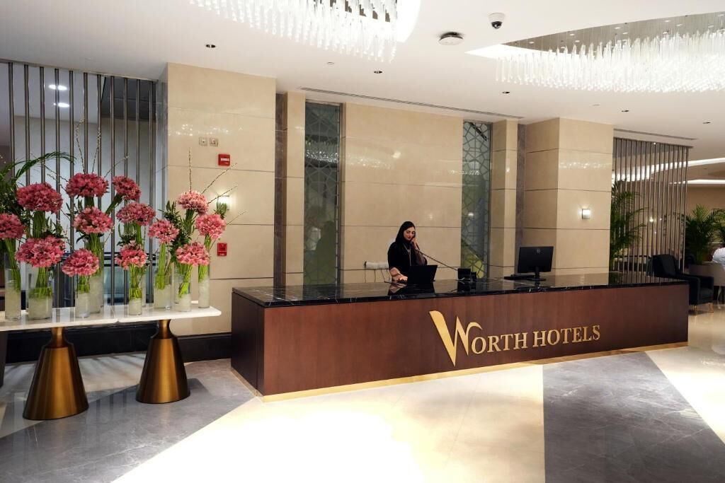 Una recepción en el hotel Westin con un diseño moderno, que presenta un gran jarrón con flores rosas y un recepcionista detrás del mostrador.