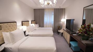 Une chambre d’hôtel avec deux lits, un bureau, une télévision et un lustre.