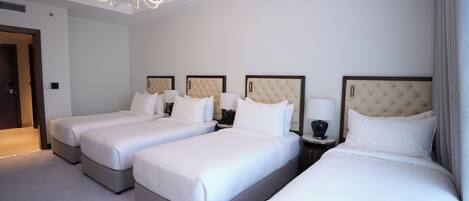 A hotel room with three beds, a chandelier, and a door.