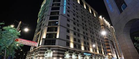 Un hotel de varios pisos con un diseño moderno, que destaca por una entrada llamativa y señalización iluminada.