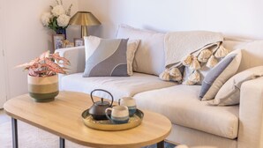 Un salon chaleureux avec un canapé, une table basse en bois, un service à thé et une plante en pot.