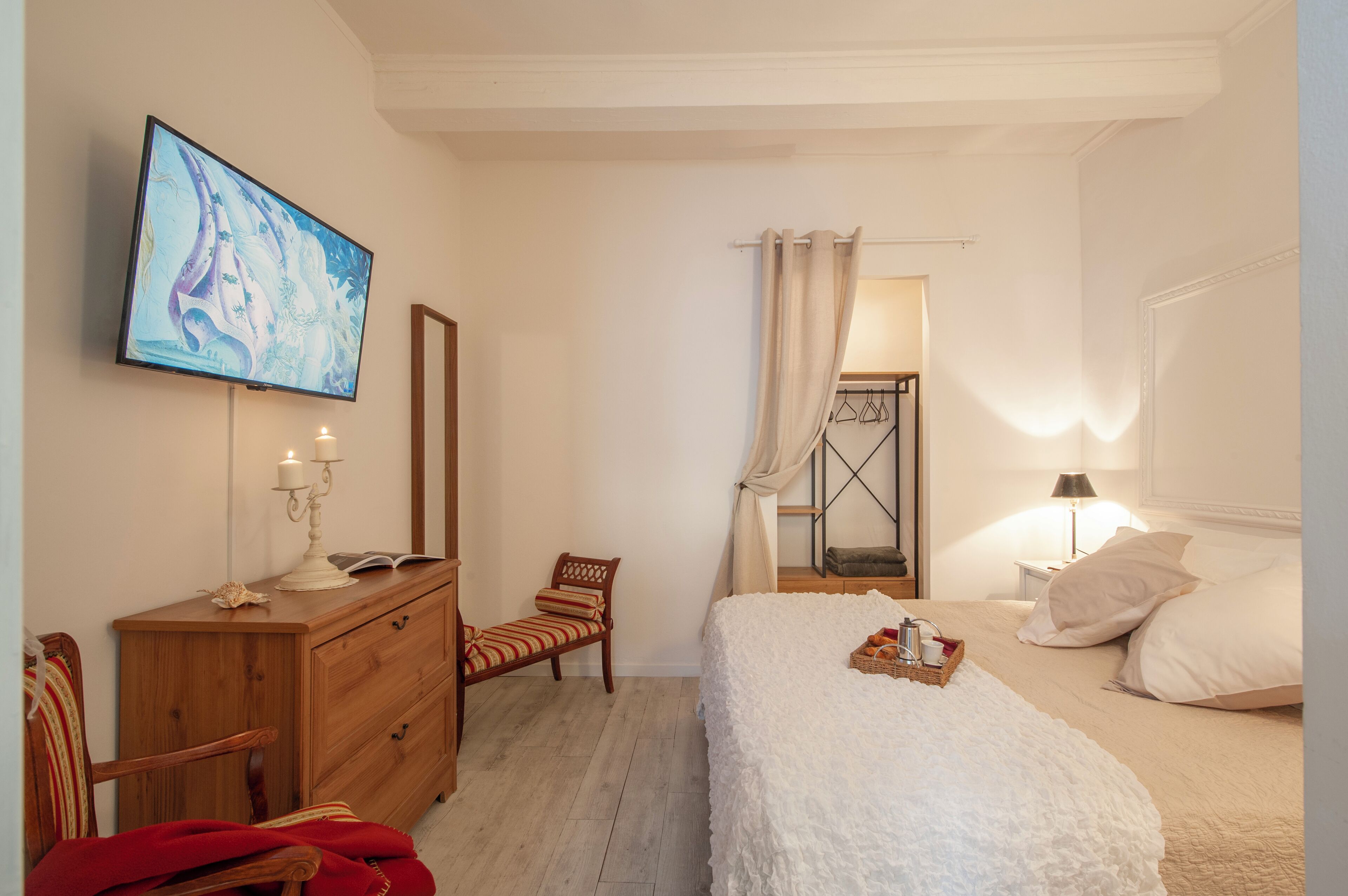 A bedroom with a bed, a dresser, a chair, a television, and a mirror.