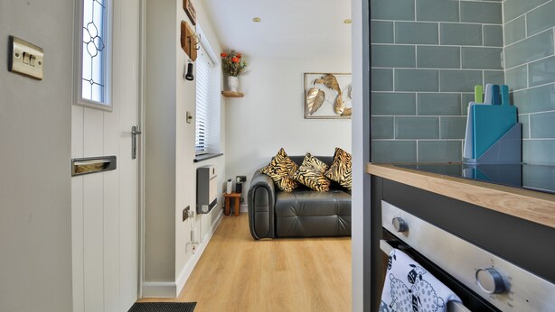 A modern kitchen with a black countertop, a built-in oven, and a wooden cabinet. - Cosy Central Cardiff Bungalow (Cardiff)