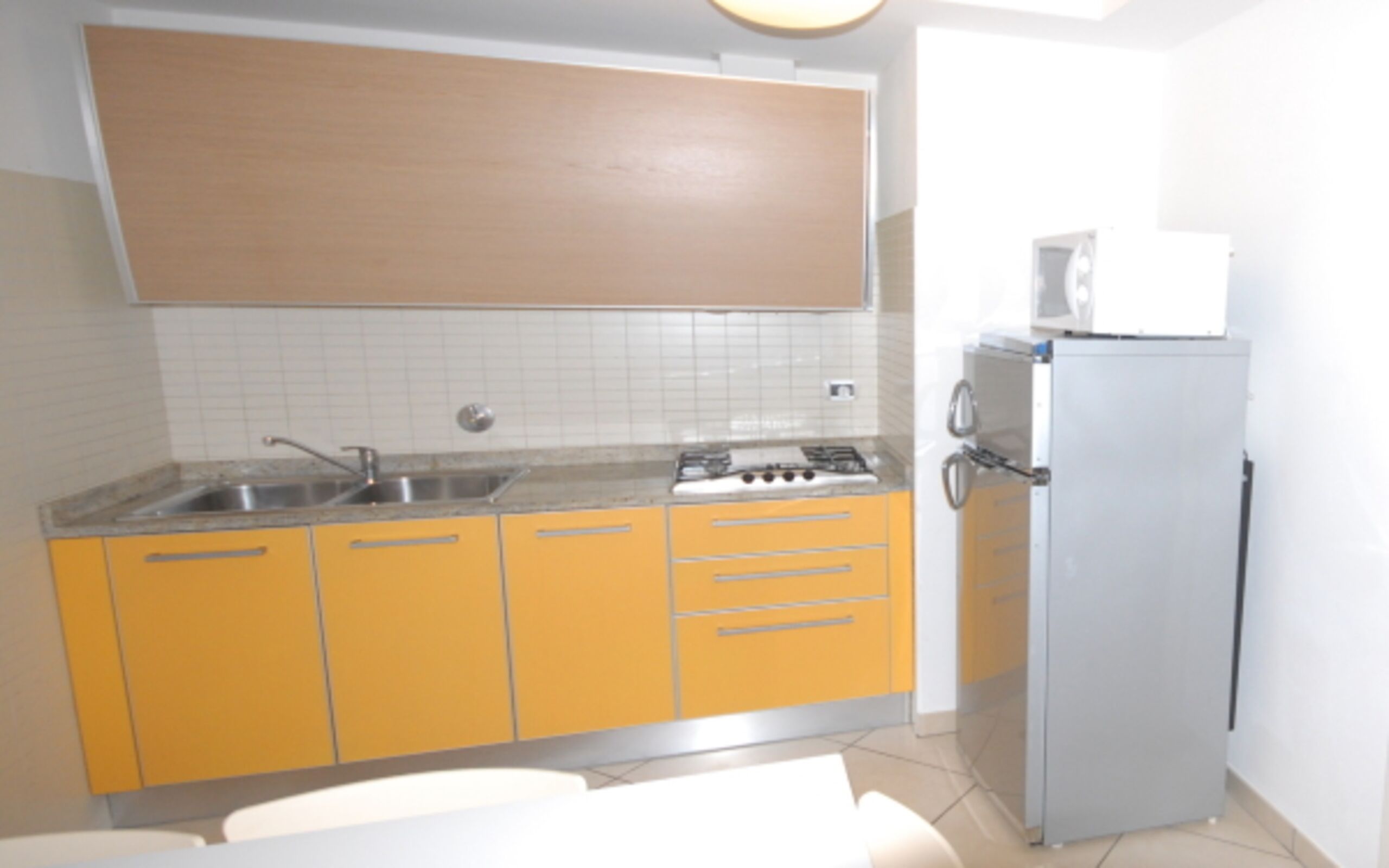 A kitchen with yellow cabinets, a sink, a stove, and a refrigerator.