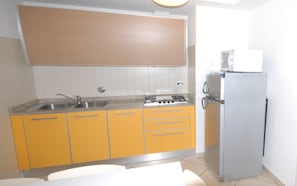 Une cuisine avec des meubles de couleur jaune, un évier, une cuisinière et un réfrigérateur.