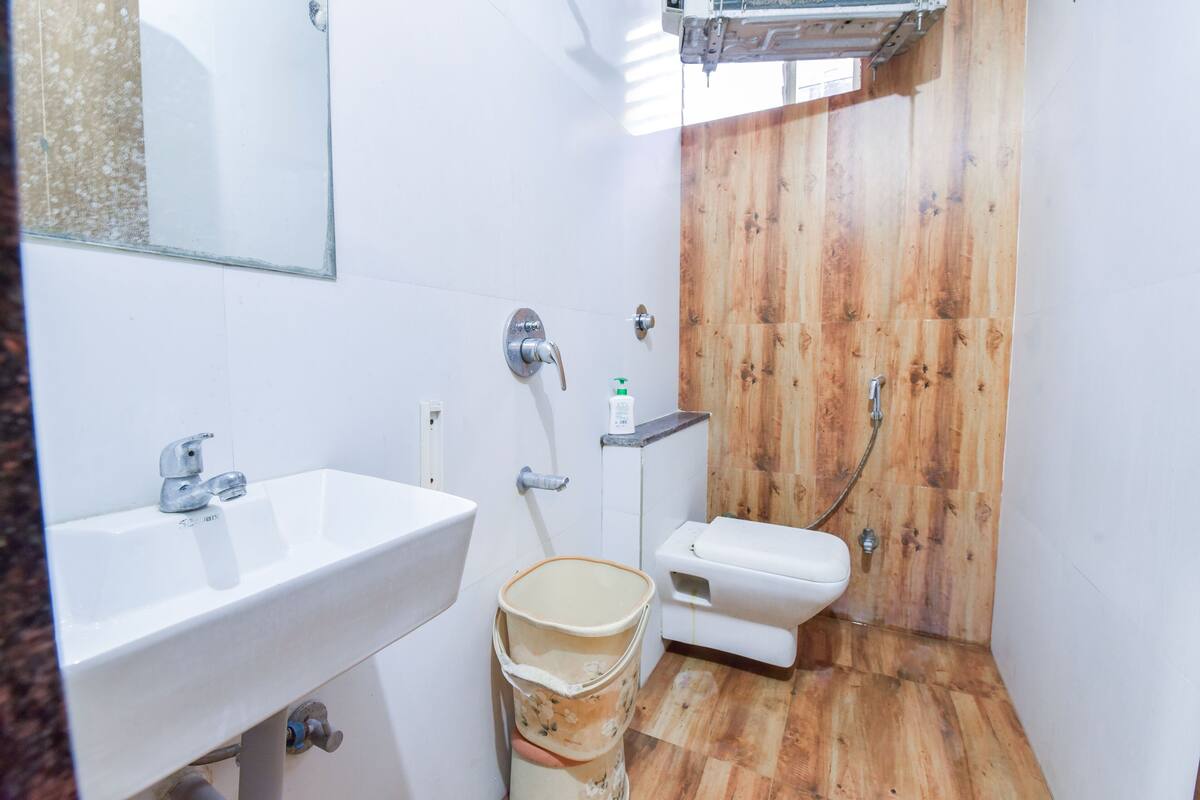 Un baño pequeño con cabina de ducha de madera, un lavamanos blanco y un inodoro.