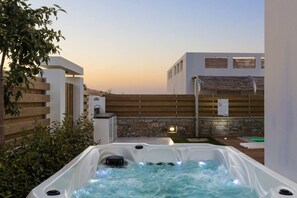 A hot tub in a modern outdoor setting with a wooden fence and a stone wall. - Eeanthe by the beach! Thalasses (rethymno)