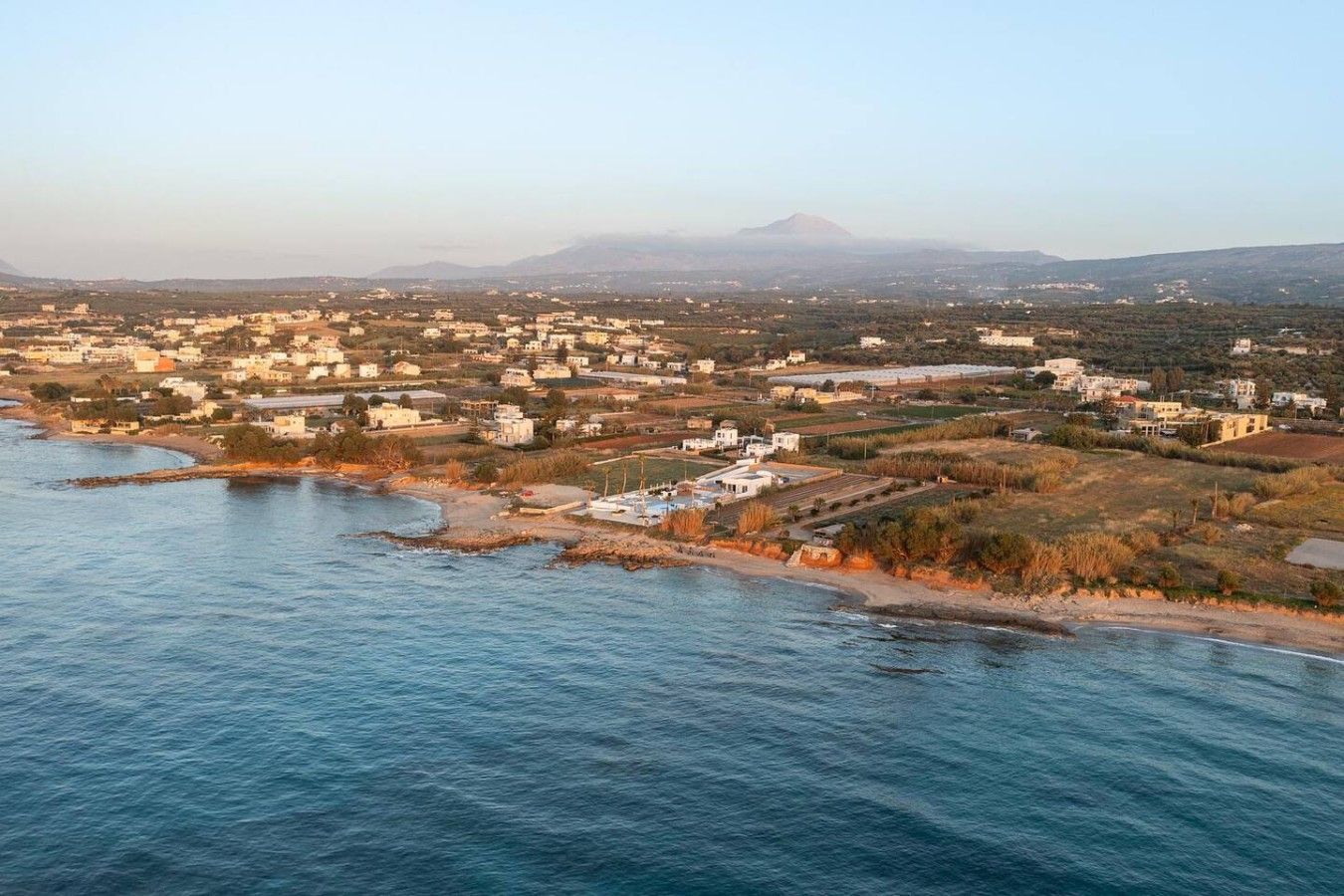 A coastal town with buildings along the shoreline and a mountain in the background.