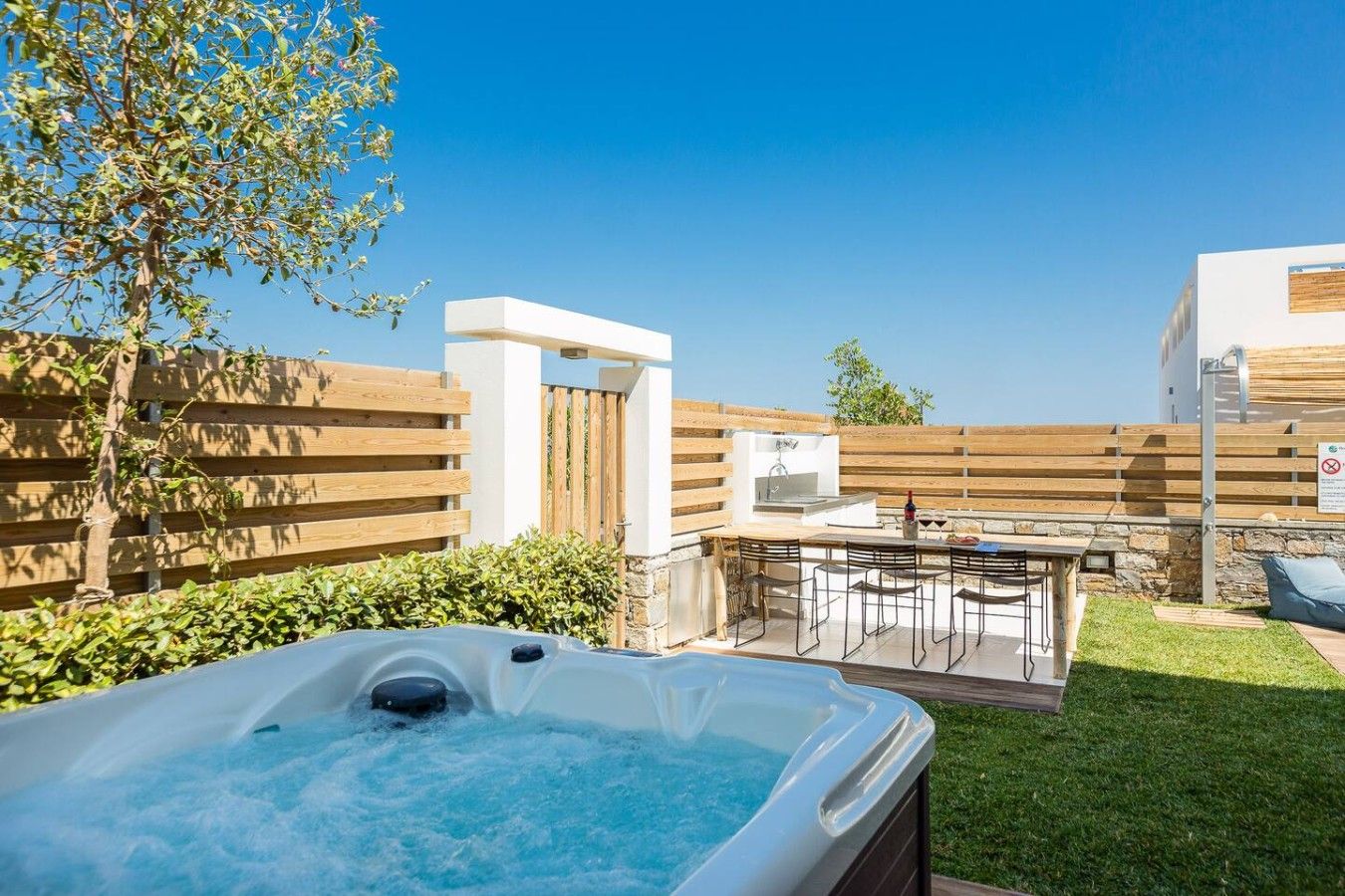 Ein Garten mit Whirlpool, Grillplatz und Holzzaun.