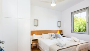 Un dormitorio con cama, mesita de noche y ventana con vistas a la vegetación.