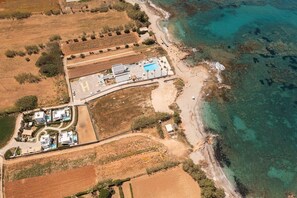 Luftaufnahme eines Anwesens an der Küste mit Schwimmbad, Helikopterlandeplatz und Strand.
