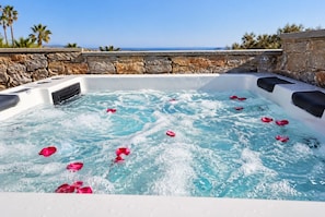 A hot tub with water, stone walls, and a view of the ocean. - Persi by the beach! Thalasses villas (Rethymno)