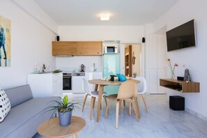 A modern apartment with a living room, dining area, kitchen, and a TV mounted on the wall.