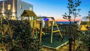 Un bâtiment moderne doté d’une structure de jeu en bois et d’une balançoire, le tout situé dans un espace jardin.