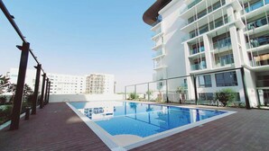 A rooftop swimming pool with a clear blue sky in the background. - Bloomfields Euphoric STU in Oasis Masdar (Abu Dhabi)