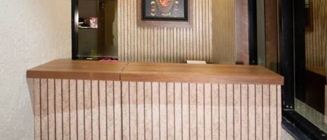 A reception desk with vertical paneling, a framed artwork above it, and a ceiling light fixture.