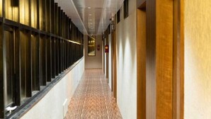A long, narrow hallway with a patterned floor, flanked by walls with vertical panels and recessed lighting.