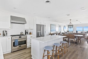A spacious kitchen with white cabinetry, stainless steel appliances, and a large island with bar stools.