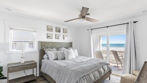 Une chambre avec un lit, un ventilateur de plafond, une fenêtre et une vue sur la plage.