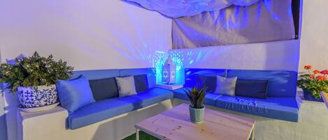 A modern lounge area with a blue sofa, a wooden coffee table, and a decorative plant.