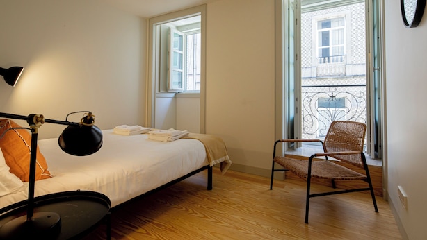 Un dormitorio con cama, una silla, un escritorio y una ventana.