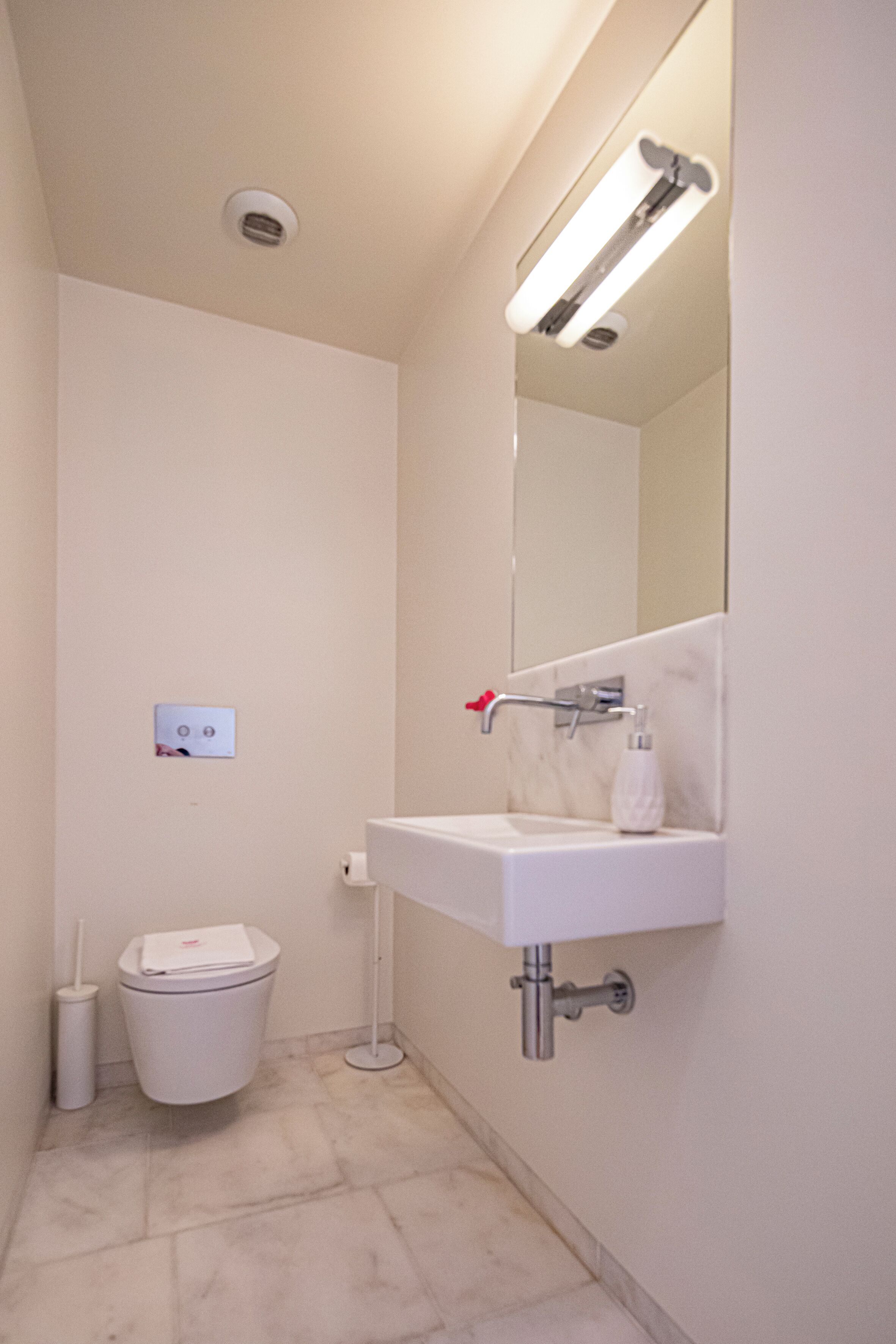 A modern bathroom with a white sink, mirror, and toilet.