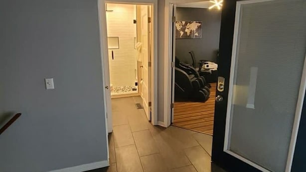 A hallway with a wooden floor, a door with a black frame, and a wall with a world map. - Remodeled and Inviting Free EV Charging Station Level 2 (Fenton)