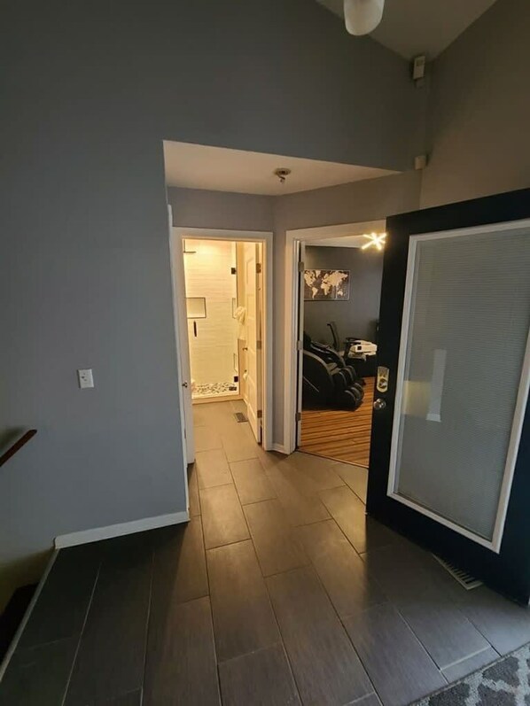 A hallway with a wooden floor, a door with a black frame, and a wall with a world map.