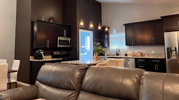 A modern kitchen with dark cabinetry, stainless steel appliances, and pendant lighting. - Remodeled and Inviting Free EV Charging Station Level 2 (Fenton)