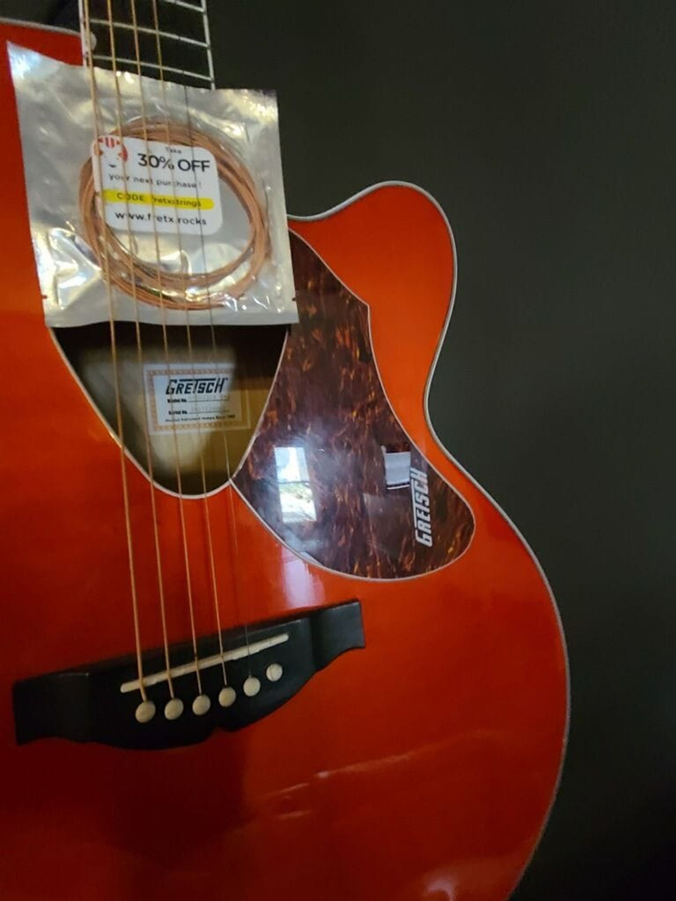 A red acoustic guitar with a white label indicating a 30% discount.