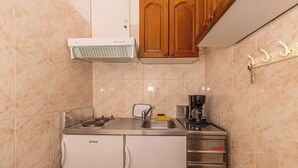 Een functionele keuken met een inbouwfornuis, een koffiezetapparaat en een kleine koelkast.