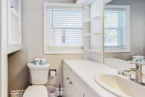 Een badkamer met toilet, wastafel en raam met zonwering.