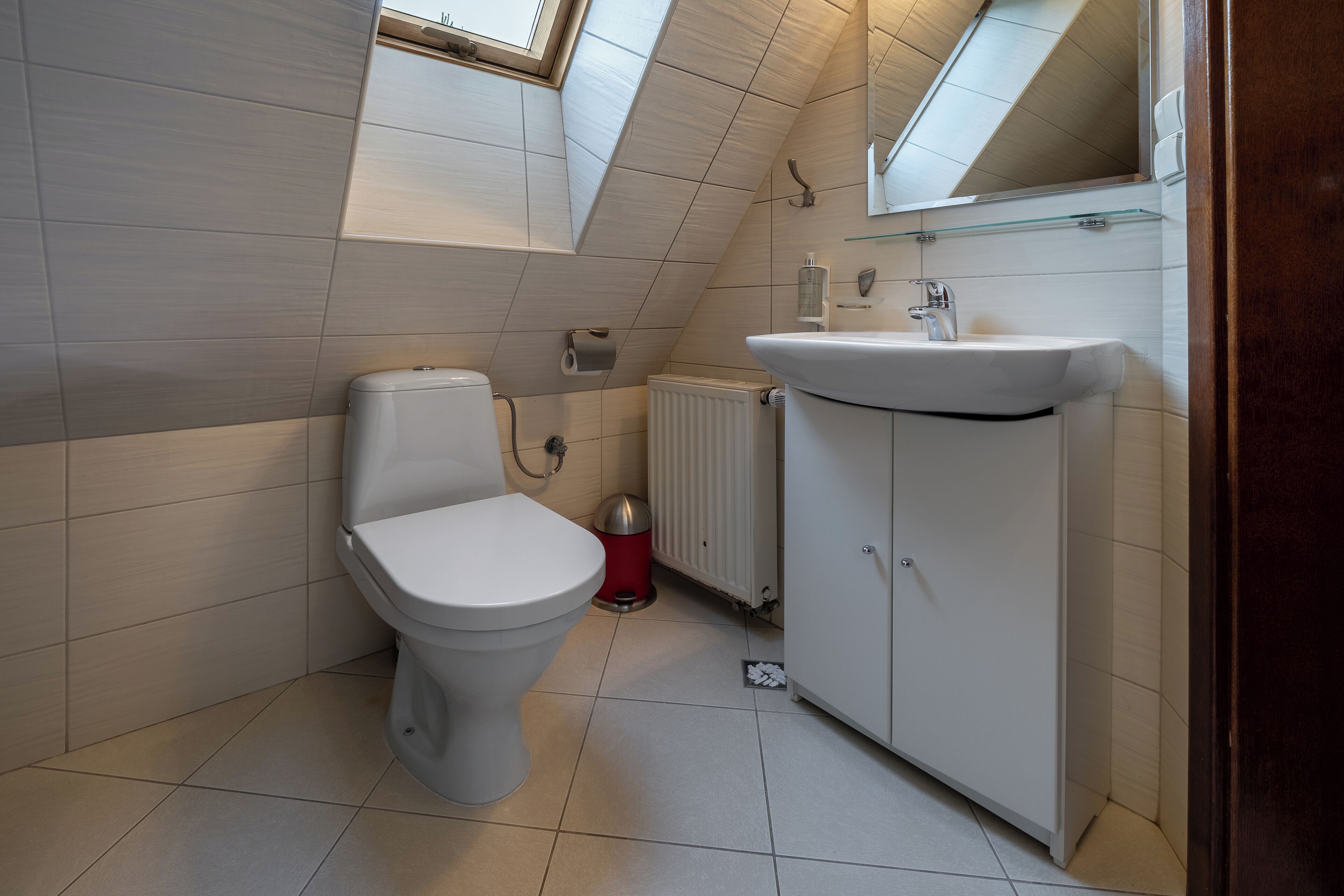 A modern bathroom with a toilet, sink, and storage cabinet.