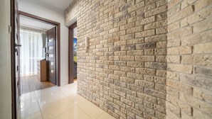 Passadís amb paret de maó i porta de fusta que dona a una habitació.