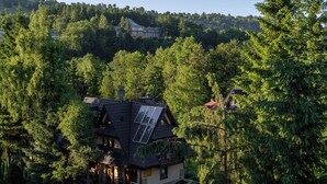 Una casa envoltada de bosc dens, amb teulada inclinada i panells solars.