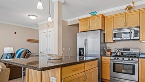A modern kitchen with wooden cabinets, stainless steel appliances, and a granite countertop.