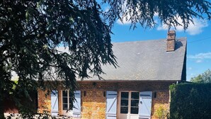 A brick house with a tiled roof, a chimney, and a garage door. - Le Cellier Vacation Rental - A Break in the Countryside (Boissay)