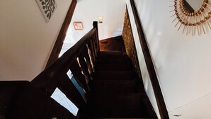 A wooden staircase with a handrail, white walls, and a decorative mirror on the right. - Le Cellier Vacation Rental - A Break in the Countryside (Boissay)