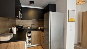 A modern kitchen with a wooden island, stainless steel appliances, and a small wooden stool. - Apart  with heated pool by Pinarello Villa Services (Lecci)